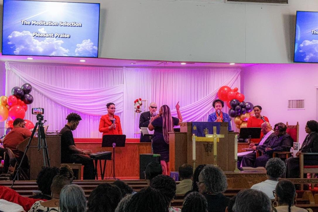 A celebration service with musicians and leaders at the front of the sanctuary, decorated with balloons