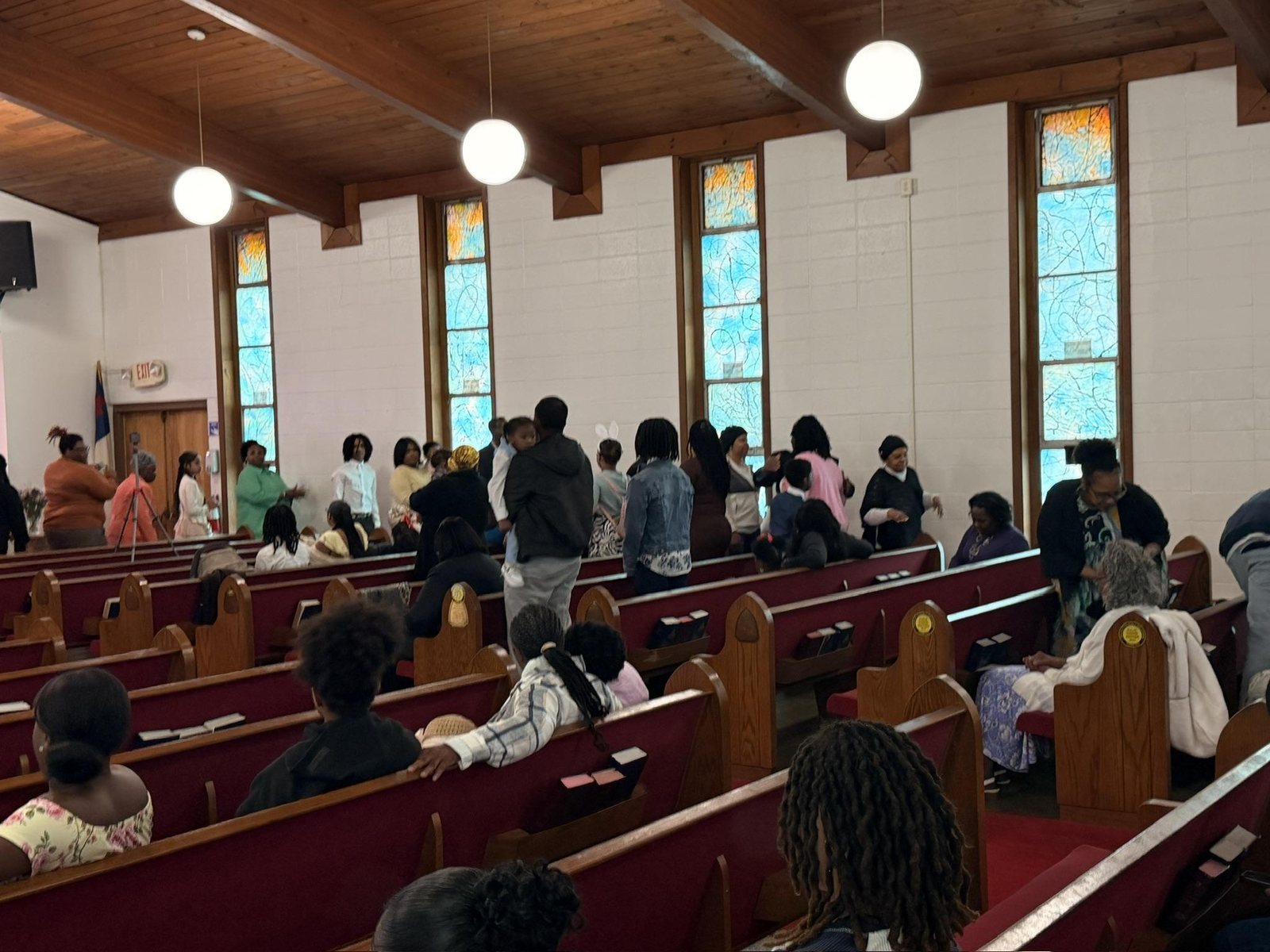 Members seated in the wooden pews beneath tall stained-glass windows