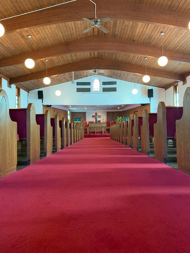 The sanctuary before the renovation, looking down the red-carpeted aisle between wooden pews
