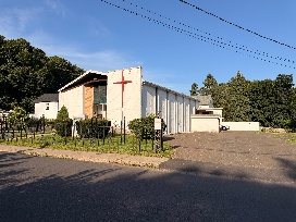 The church building on Rowan Street with its tall red cross and iron fence