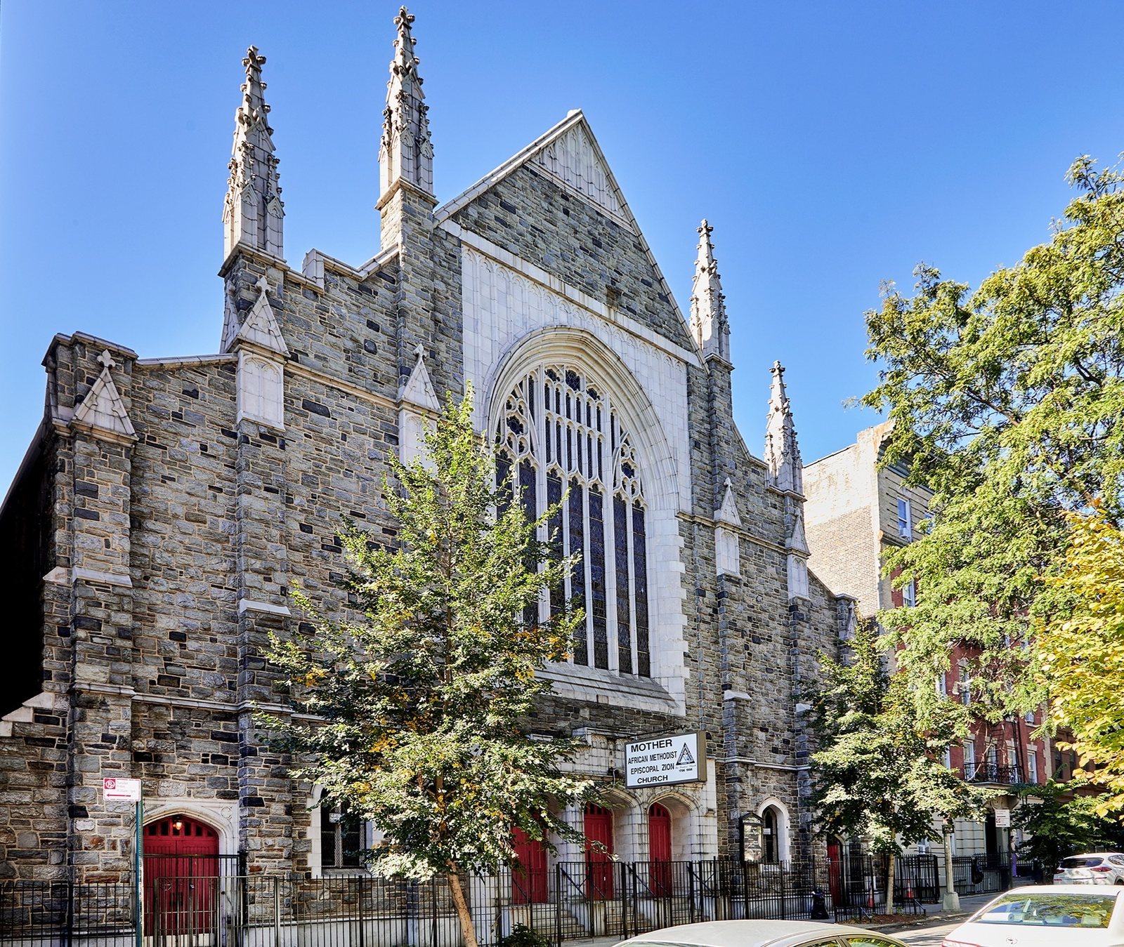 Mother African Methodist Episcopal Zion Church in Harlem: a grey stone Gothic church with spires, a tall arched stained-glass window and red doors