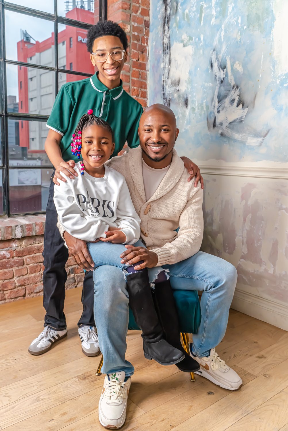 Rev. L. Christopher Lewis seated with his two children, his son standing behind him and his daughter on his knee