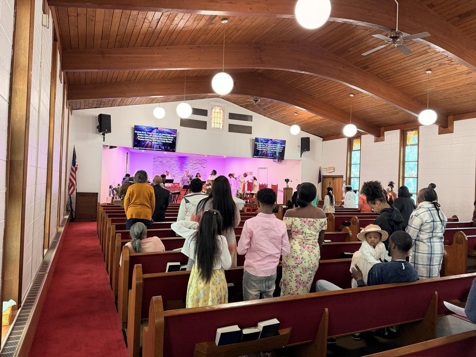 Families and children standing in the pews along the red-carpeted centre aisle