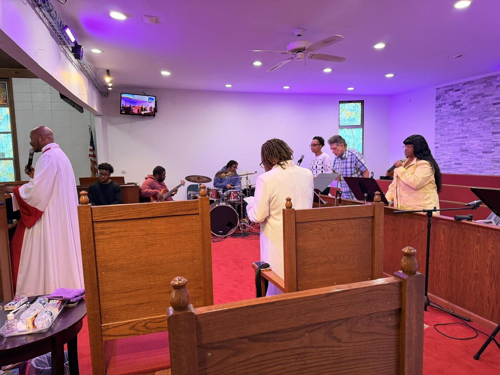 Musicians on drums and keys with singers leading worship at the front of the sanctuary